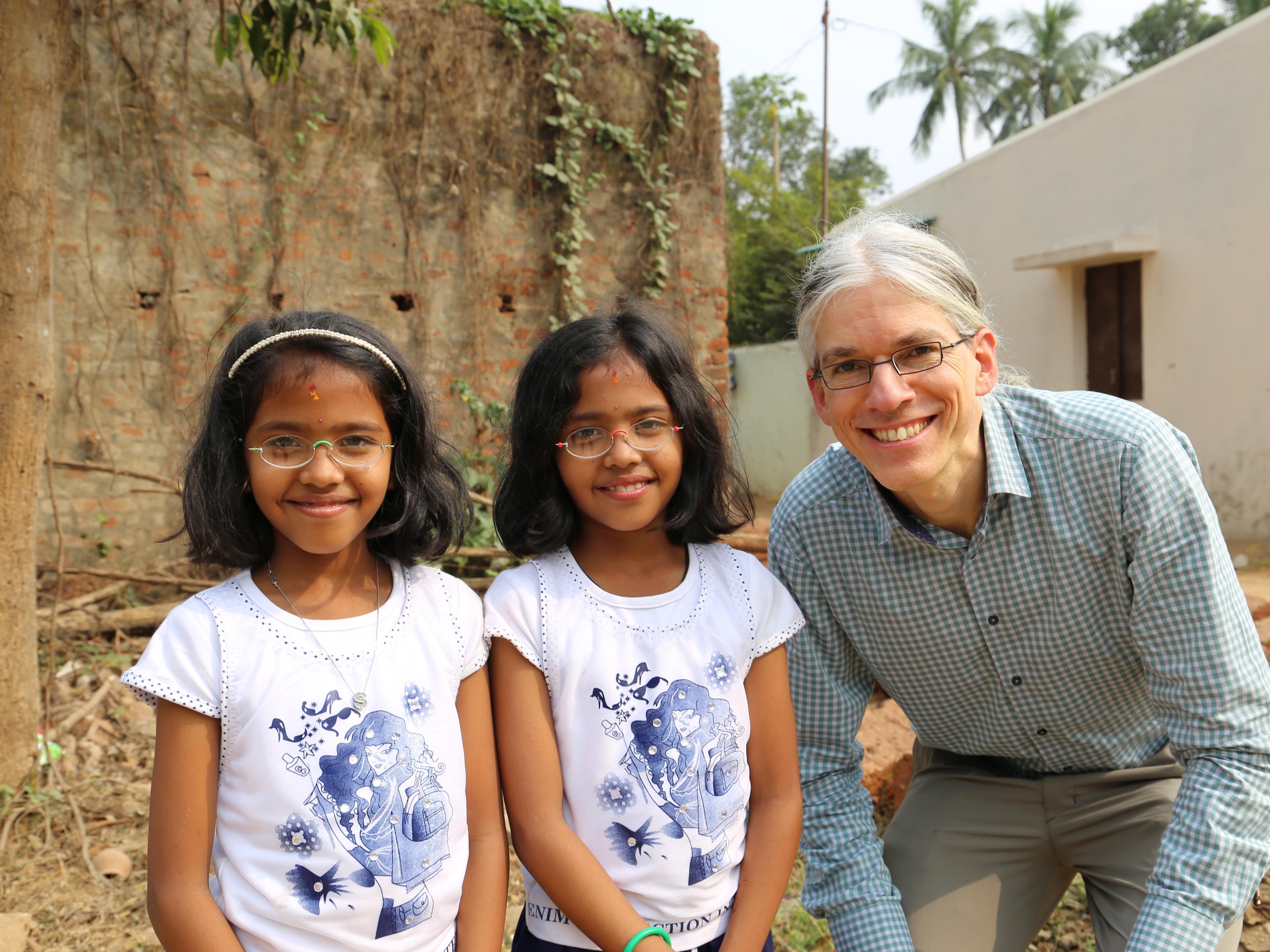 Martin Aufmuth neben Zwillingsmädchen in Indien, die Mädchen tragen EinDollarBrillen